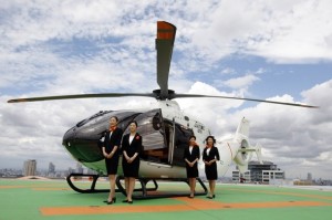 Staff line up during a photo opportunity in front of Japan's first Hermes helicopter, designed by the French luxury brand in conjunction with Eurocopter, during a media event to announce Mori Building City Air Services' private helicopter service in Tokyo August 7, 2009. The service will provide a 30-minute luxury helicopter shuttle service between central Tokyo and Narita International Airport using Eurocopter choppers, including a $10 million EC135 model designed by Hermes. The fare for a one-way ride is 75,000 yen ($790). REUTERS/Yuriko Nakao (JAPAN SOCIETY TRANSPORT BUSINESS TRAVEL IMAGES OF THE DAY)